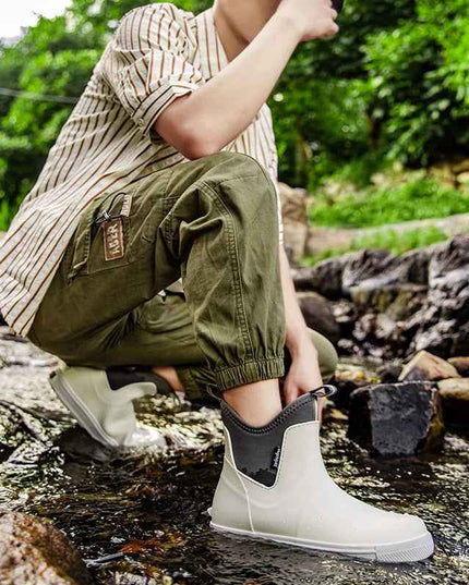 Model draagt Elin regenlaarzen bij het aantrekken op rotsen